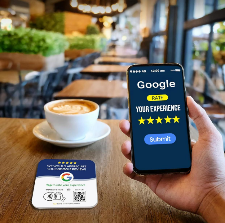 Customer at a café table tapping their phone on an NFC Google review card, phone showing a rate-your-experience screen